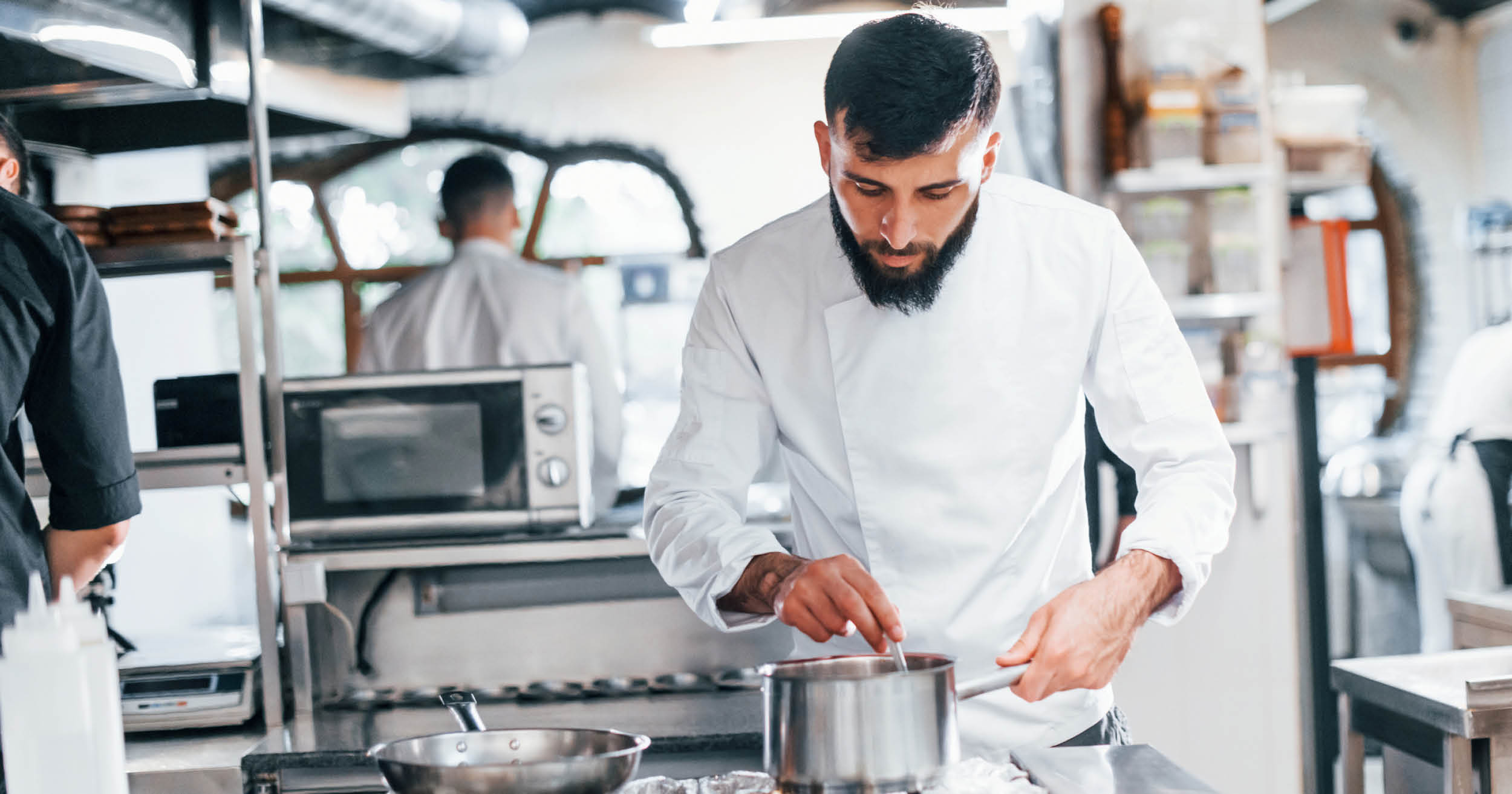 man stirring pot of soup in kitchen